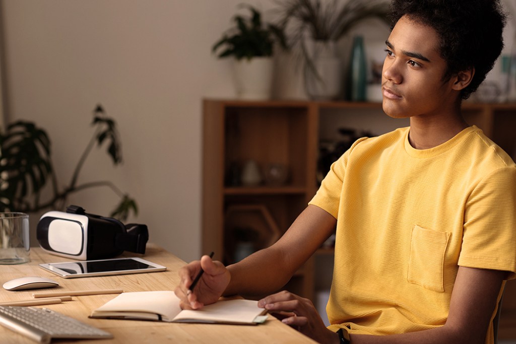Boy thinking with a pencil and notepad at hand
